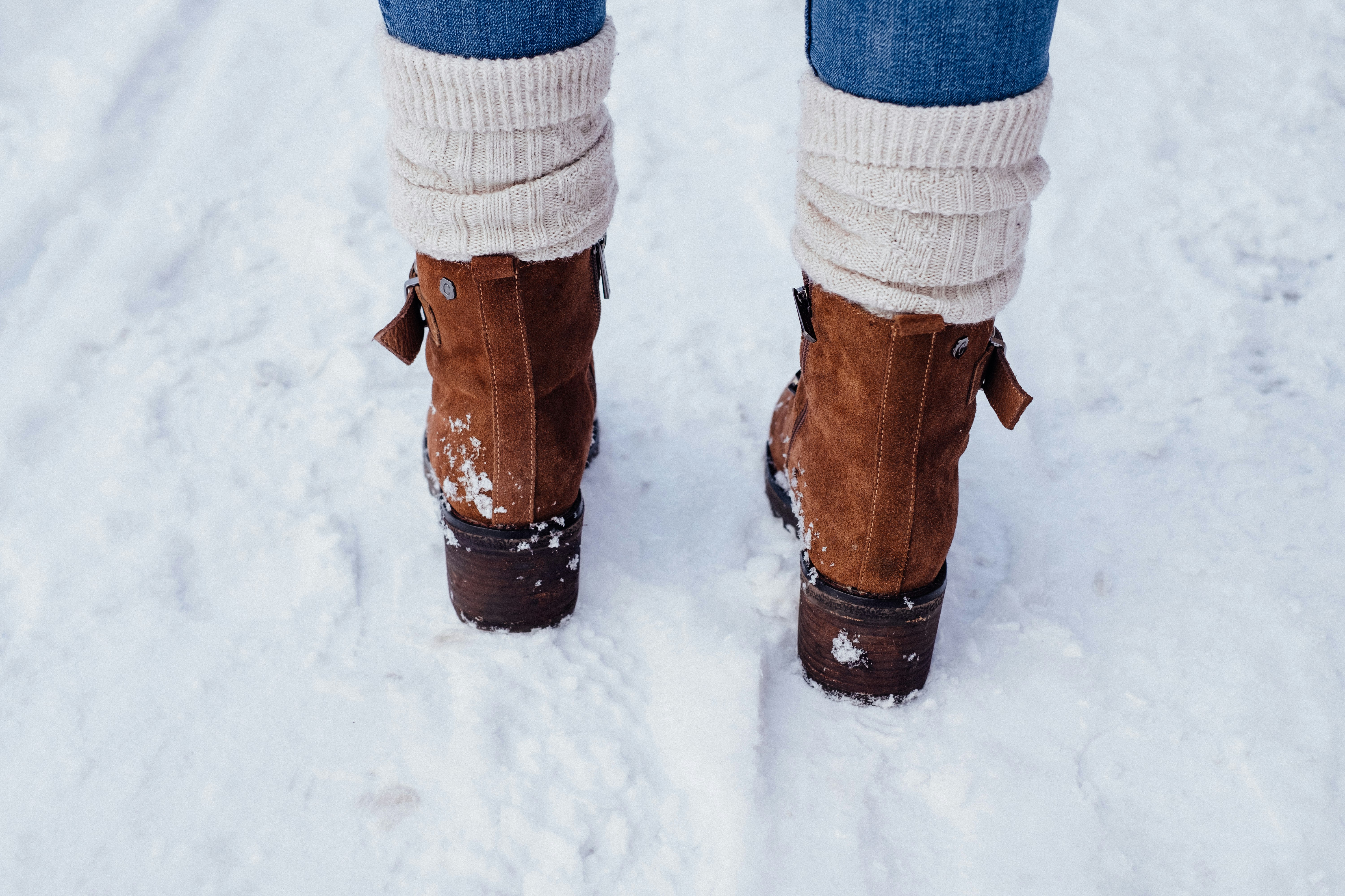 person in brown leather boots standing on snow covered ground